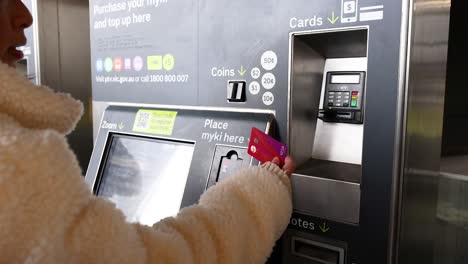 person topping up myki card at machine