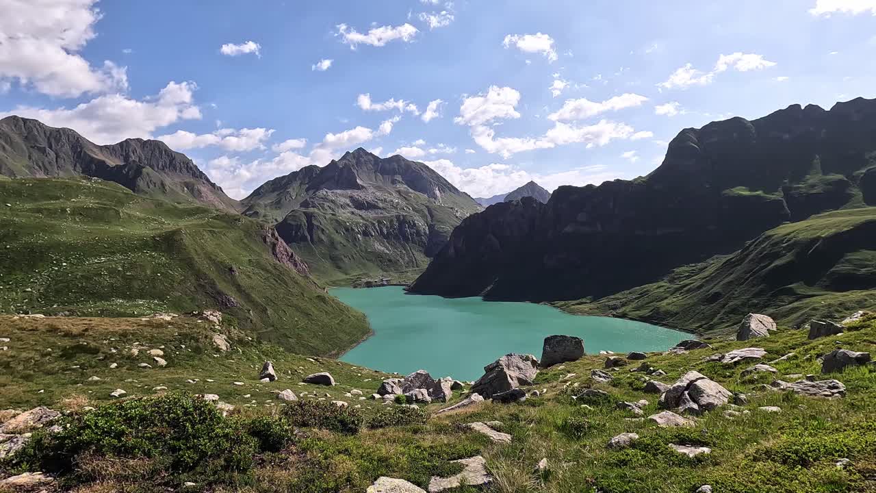 High Viewpoint Overlooking the Turquoise Waters of Lago Vannino in the Lepontine Alps, Piedmont, Italy, Surrounded by Green Ridges and Dramatic Rocky Peaks Under a Partly Cloudy Sky