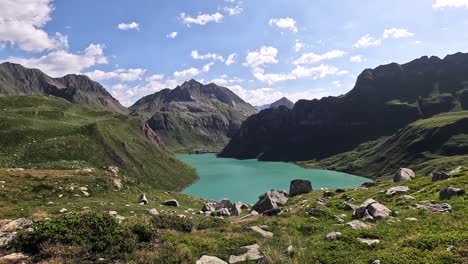 high viewpoint overlooking the turquoise waters of lago vannino in the lepontine alps, piedmont, italy, surrounded by green ridges and dramatic rocky peaks under a partly cloudy sky