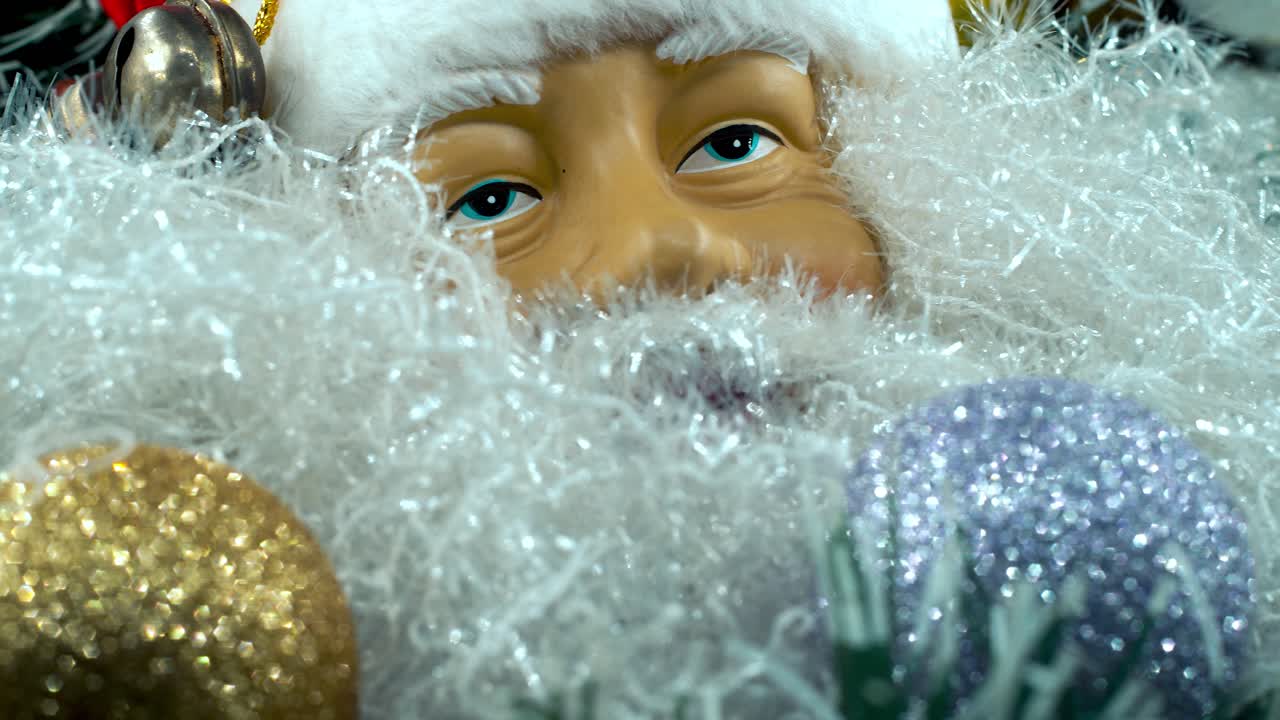 Detailní záběr zblízka, plynulý posun doleva, hračka Santa Claus v červené čepici se zvonečky, vánoční dekorace, tradiční sváteční dárky, novoroční výzdoba, lesklé barevné dárky, 4K video