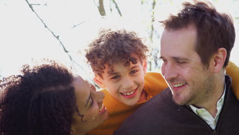 Outdoor-Portrait-Of-Loving-Parents-Giving-Son-Piggyback-Ride-In-Garden