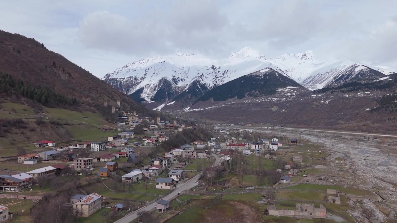 Ortaçağ Svan kulelerinin muhteşem karla kaplı Kafkas zirvelerinin altında durduğu Mestia'nın geleneksel köyünü sergileyen drone yükselişi.