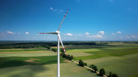 Primer-Plano-De-Las-Palas-De-Turbinas-Eólicas-Giratorias-En-Los-Campos-Verdes-De-Polonia---Vista-Aérea-Alta-Contra-El-Cielo-Azul