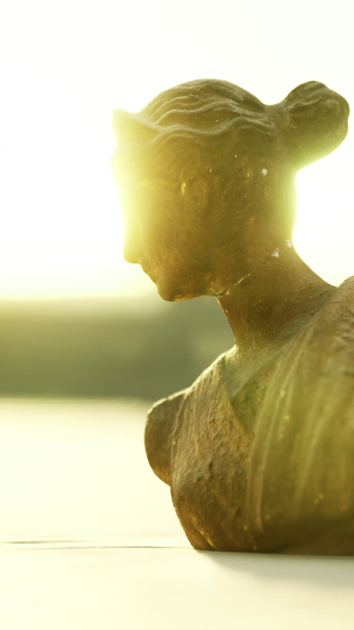Sunlit bust sculpture forms a striking silhouette at sunset