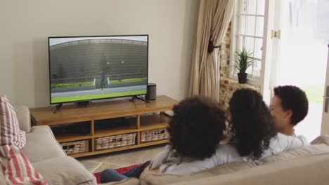 composto de uma família feliz sentada em casa juntos assistindo a um evento de atletismo de dardo na tv