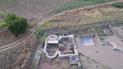 filming a drone with a top-down view of a roman villa and with a camera by raising and moving the drone backwards we discover the environment in which the roman villa is located, which are crop fields