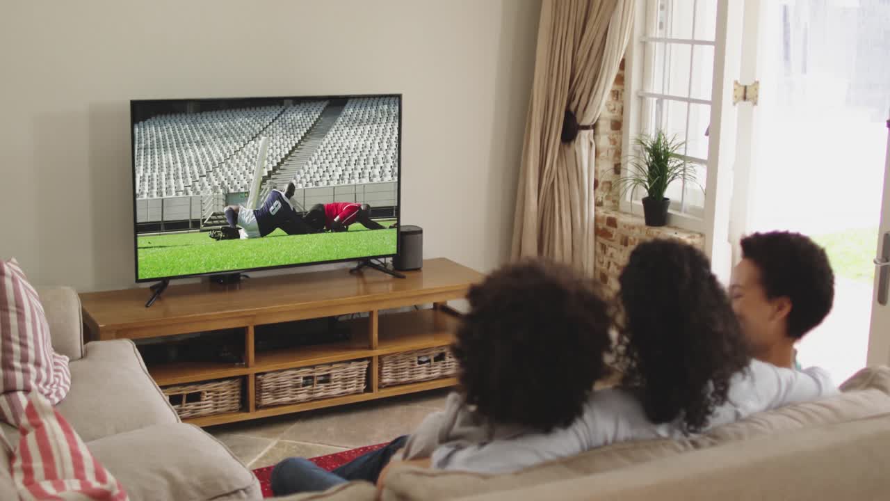 Famiglia felice seduta a casa insieme che guarda una partita di rugby in TV