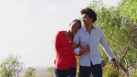 Happy-african-american-couple-walking-together-and-holding-hands-on-sunny-day,-slow-motion