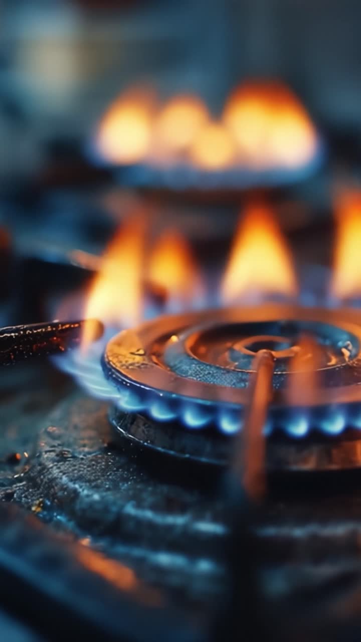 Captivating Flames Dance on a Gas Stove, Showcasing the Beautiful Blue and Orange Colors with Glimmers of Light Reflecting on the Wet Surface Around the Burners