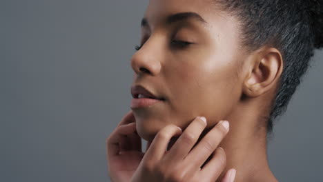 retrato en primer plano de una hermosa mujer afroamericana tocando suavemente la cara con las manos disfrutando de una piel suave y saludable, un cutis de belleza femenina natural, un concepto de cuidado de la piel