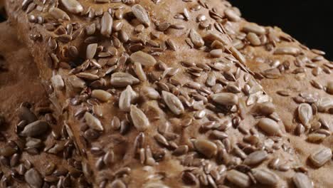 video of rotating bread with flax and sunflower seeds on black background