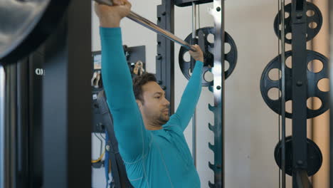 european guy doing seated barbell shoulder press in smith machine, exercise used to build shoulder strength and muscle