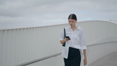 woman manager walking holding smartphone. lady reading mobile messages on go.