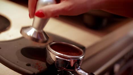 barista's hand tamping fresh ground coffee