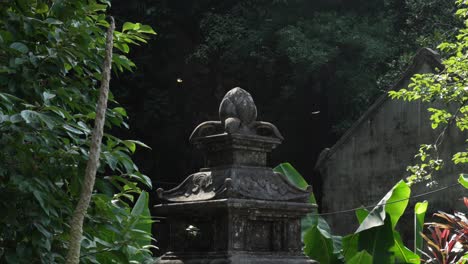 weathered stone shrine at bich dong pagoda, ninh binh, as butterflies drift in sunlit air amid tropical foliage, a heritage scene in soft light, static telephoto shot