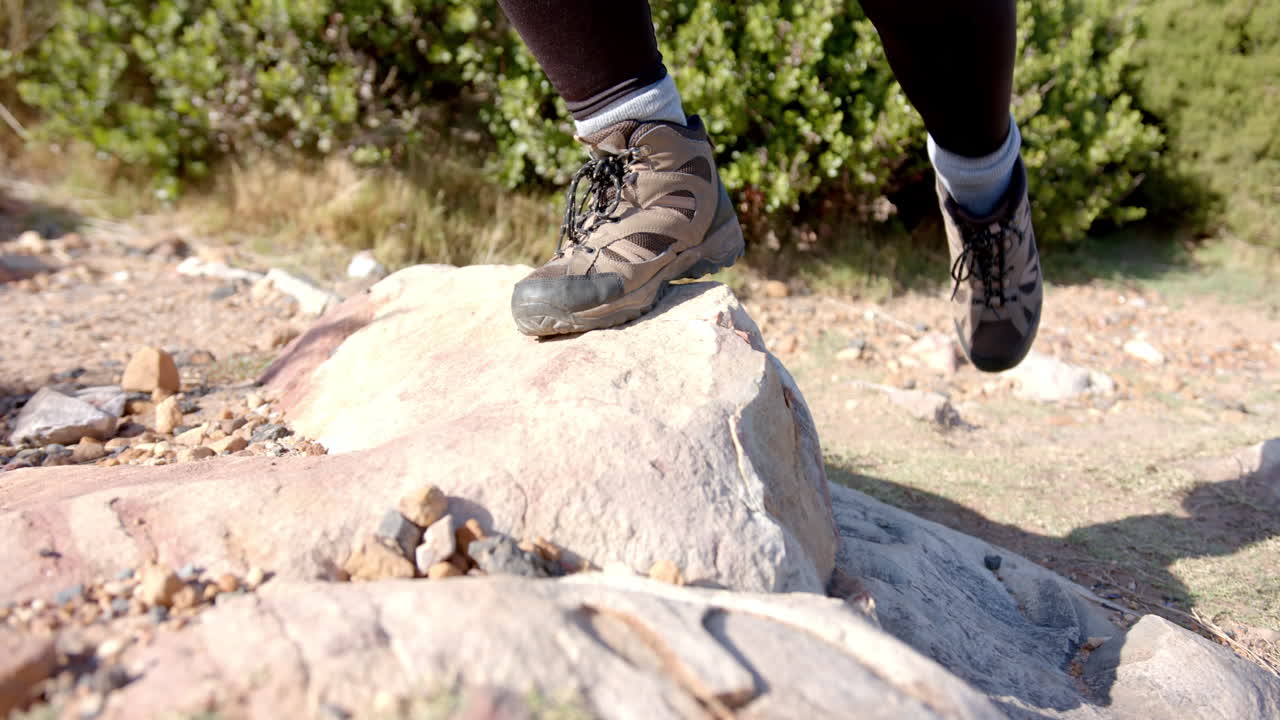 Hiking on rocky terrain, woman wearing hiking boots stepping on stone