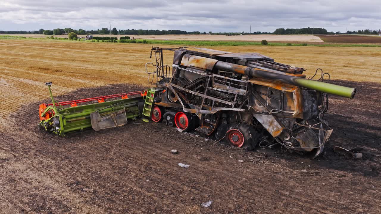 Charred harvester wreck contrasts sharply with golden fields in rural farmland