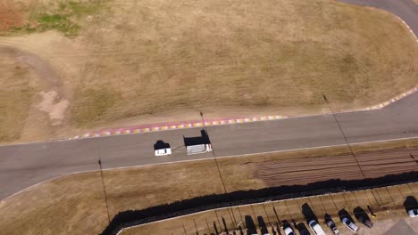 Aerial-birds-eye-view-of-tow-truck-pulling-racing-vintage-car-to-pit-stop-on-Buenos-Aires-racetrack