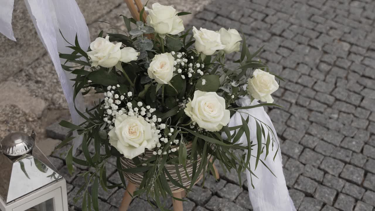White rose wedding bouquet with greenery in a rustic setting on cobblestone