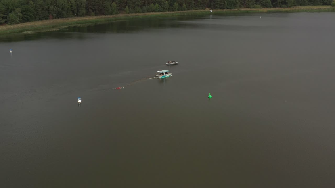 보트 뒤에 있는 롱보드에 있는 surfergirl의 드론 샷