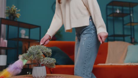 joven bailarina limpiando el polvo de los muebles sola cuidando la higiene usando polvo de colores en la habitación en casa