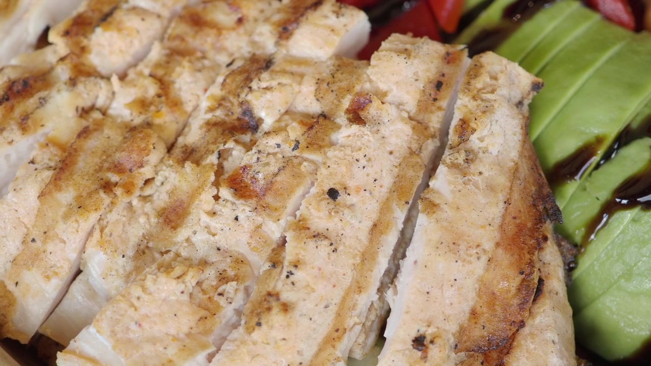 Rodajas de pollo a la parrilla servidas con aguacate fresco y garbanzos