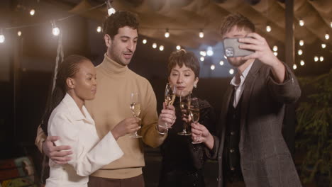 group of four happy multiethnic friends taking a selfie video and toasting with champagne glasses at new year's eve party 1