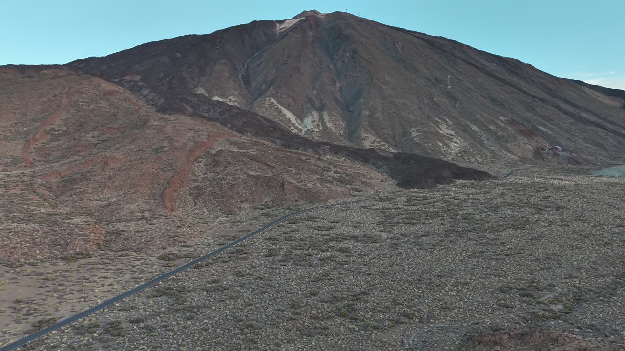 Aerial view of Mount Teide in Tenerife with a winding road leading through volcanic terrain and rugged natural landscape