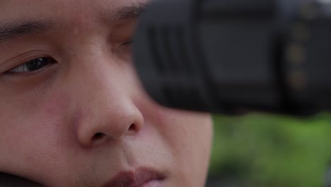 asian man aiming through a scoped air rifle outdoors in a focused close-up shot