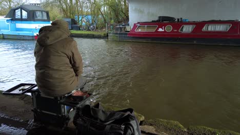 hombre solitario irreconocible pescando un canal debajo de un puente