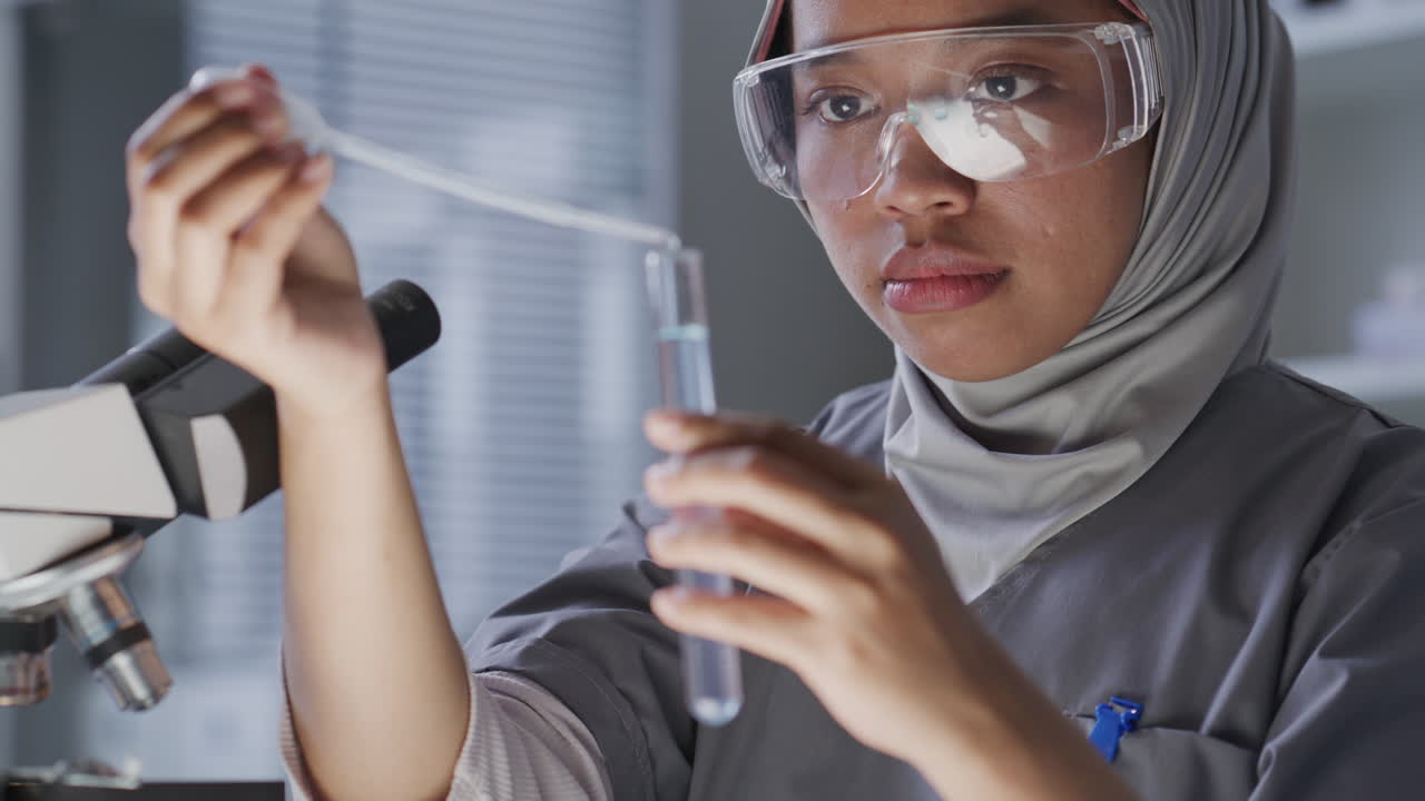 Female Chemist Transferring Liquid with Pipette into Test Tube in Laboratory