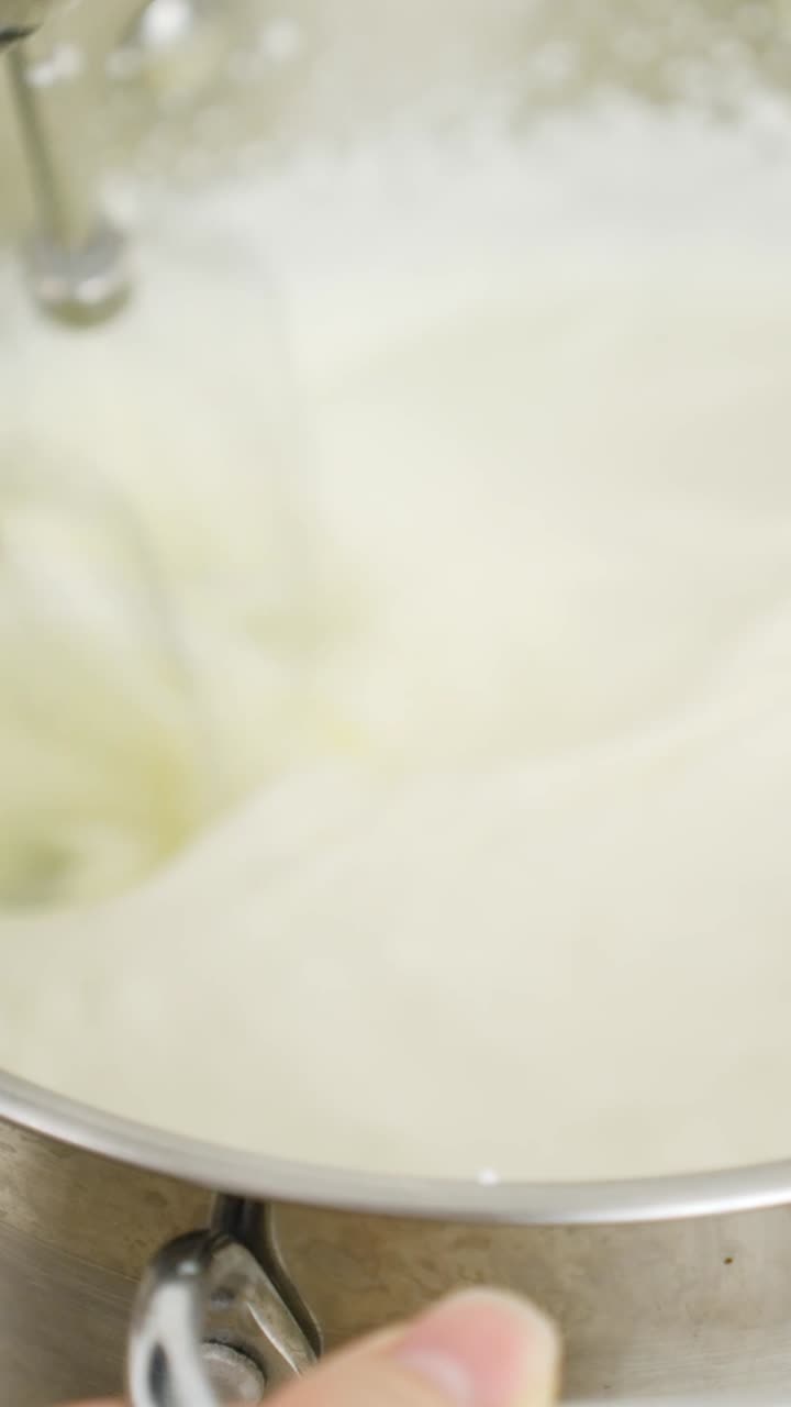 Whisking cream in a mixing bowl, preparing for tiramisu recipe creation