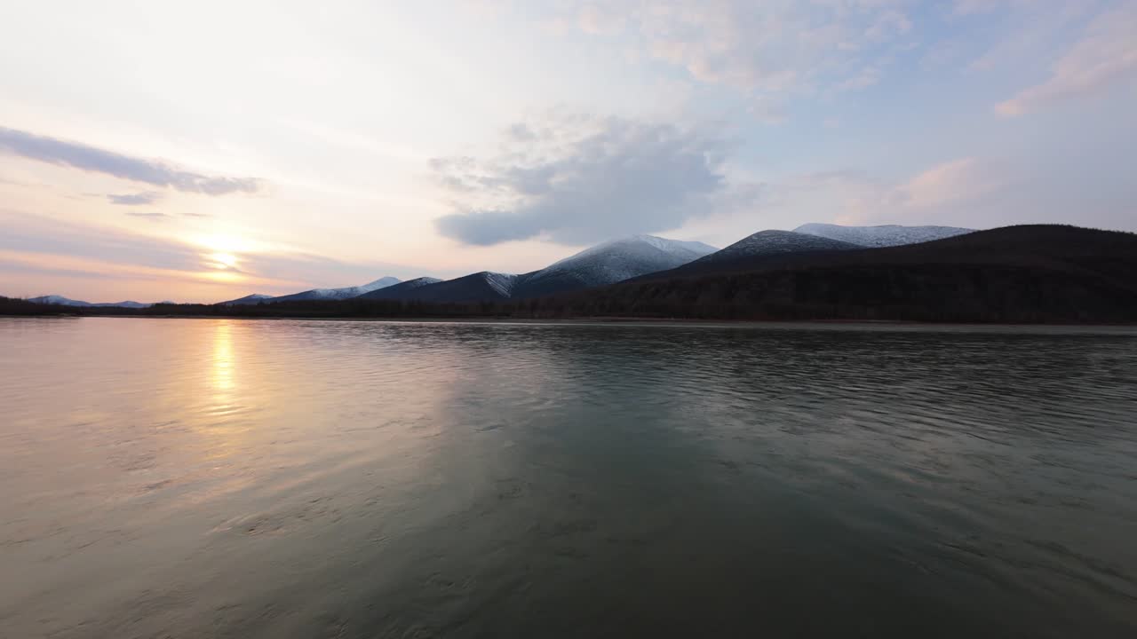 свидетель гармонии природы, когда солнце заходит за величественными горами, освещая спокойные воды.