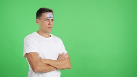 Man with israeli flag painted looking away with serious expression