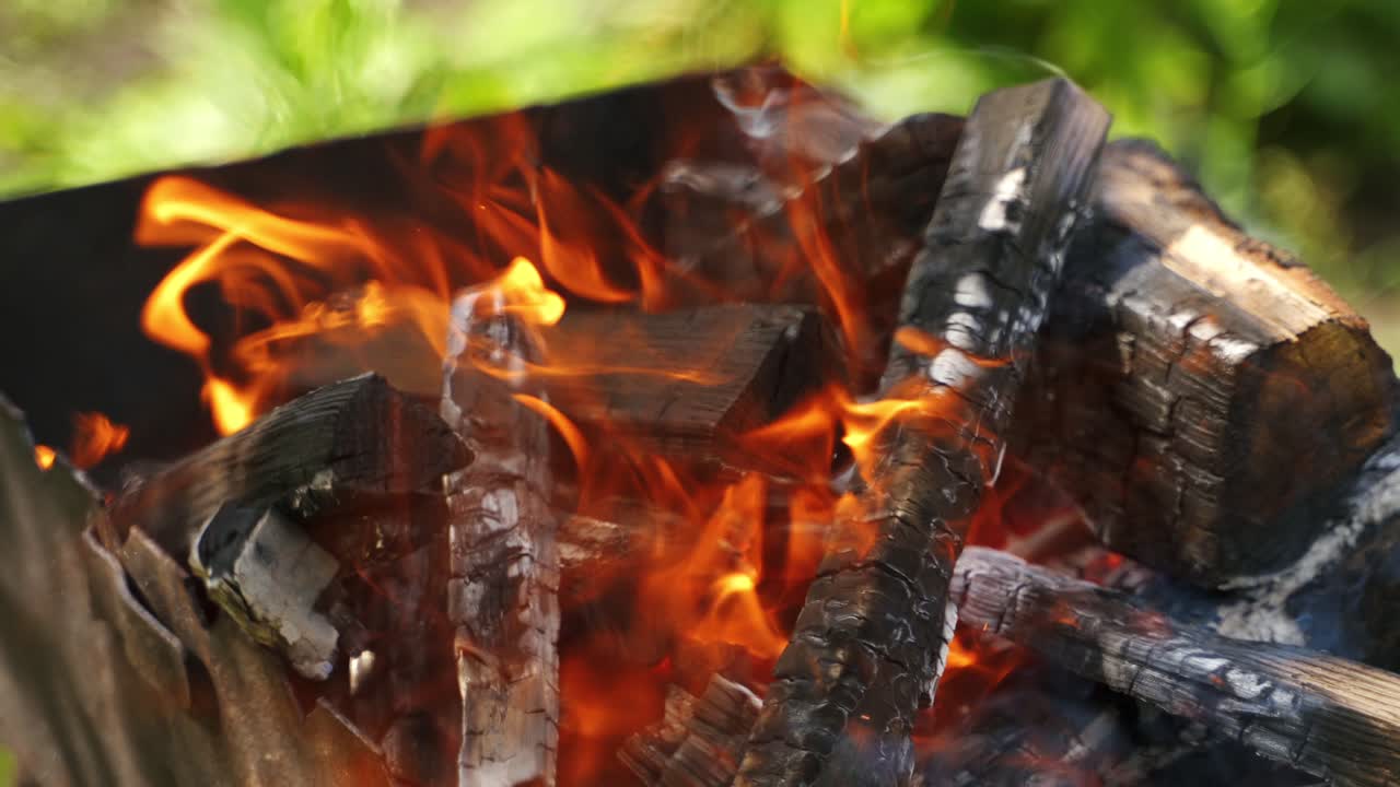 Hot charcoals in fire. Logs of wood smoldering and flaming. Wooden logs burning for barbeque outdoors.
