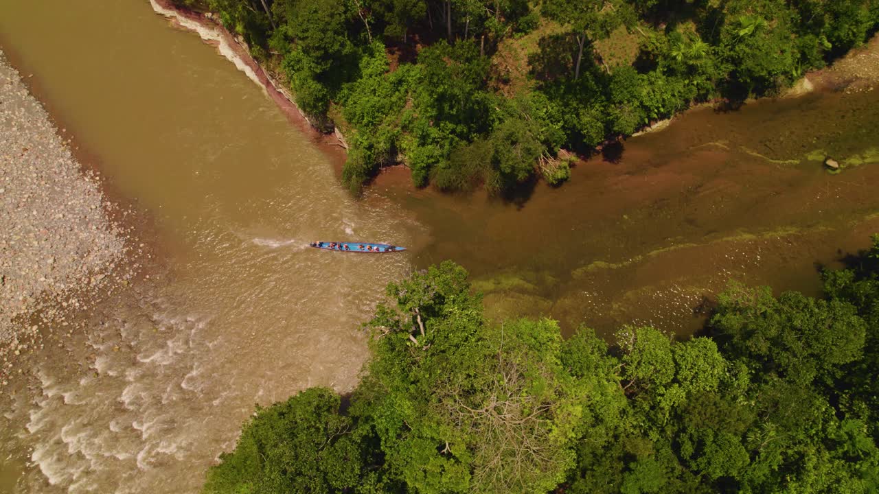 un barco tradicional navegando por las aguas fangosas de un río en oxapampa, perú, rodeado de exuberante vegetación, vista aérea