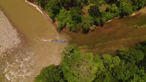 Un-Barco-Tradicional-Navegando-Por-Las-Aguas-Turbias-De-Un-Río-En-Oxapampa,-Perú,-Rodeado-De-Exuberante-Vegetación,-Vista-Aérea