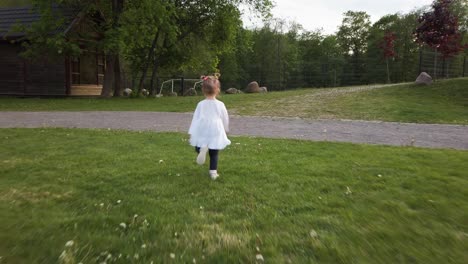 little toddler girl runs on the grass camera from behind 4k slow motion