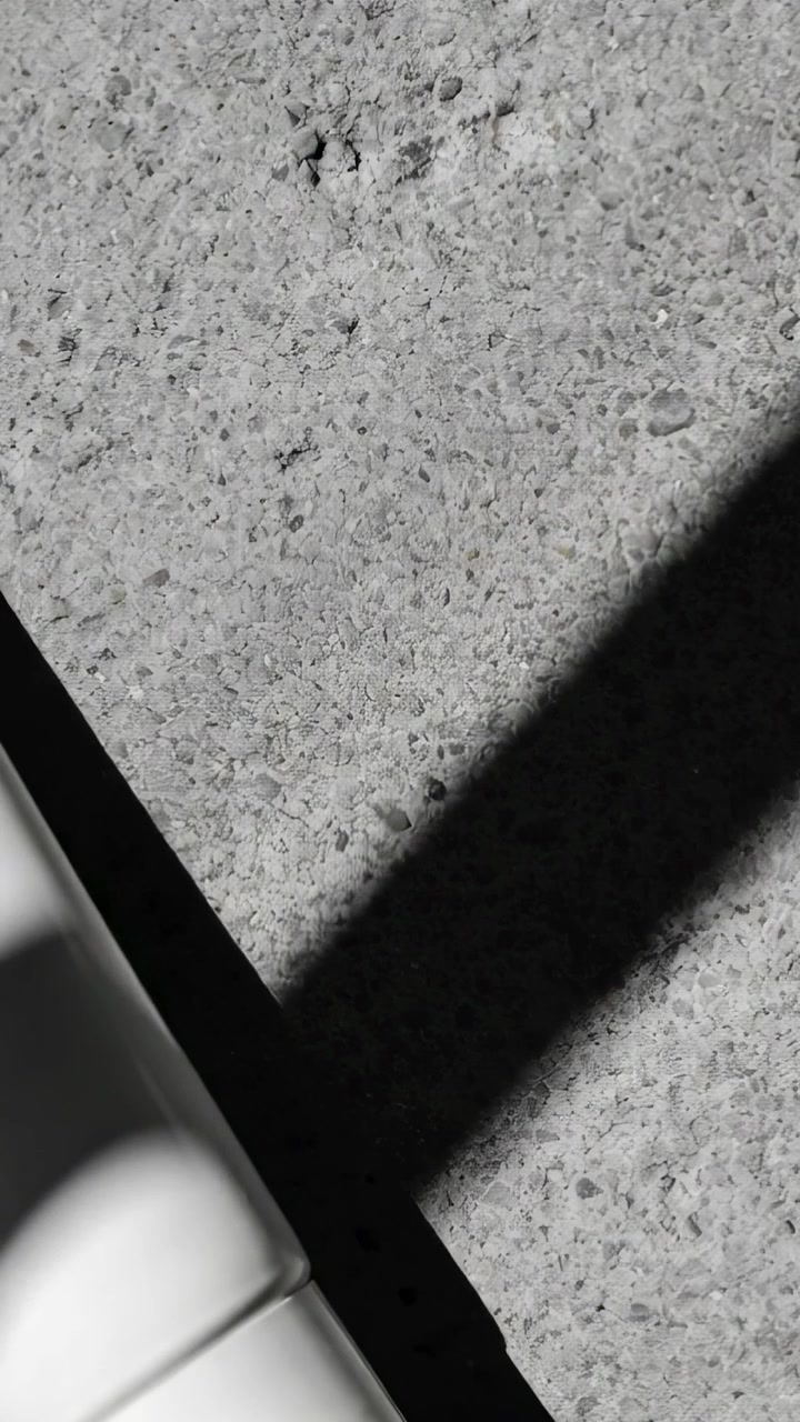 Video verticale: Telecamera che si inclina mostrando un'ombra che scivola su un patio in cemento, con una curva bianca all'angolo.