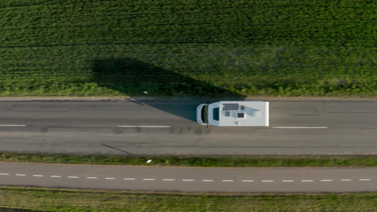 Drone su camper in viaggio lungo una strada attraverso campi verdi
