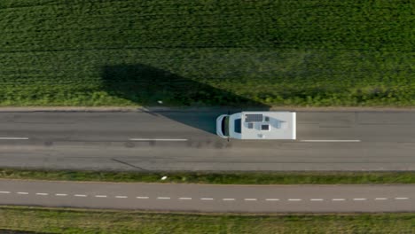 drone over campervan driving along road through green fields