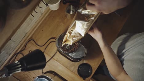 Top-shot-of-man-pouring-coffee-beans-into-coffee-maker