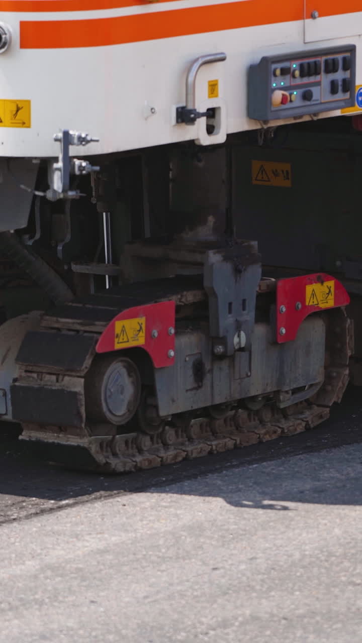 Construction During Asphalting Works. Asphalt paver machine operating during road construction and repairing works Vertical video