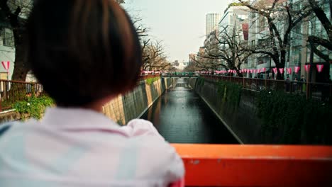 woman looking at a canal in a japanese city during spring