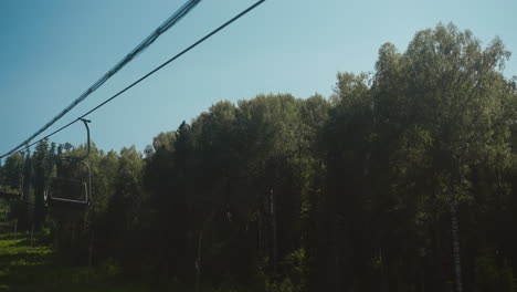 cabin lift for travellers moves in air on cableway against dense trees. video depicts amazing journey on cableway from lower station to viewing platform on mountain