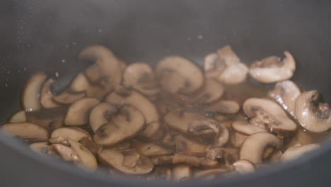 slowly simmering and releasing water from champignon porcini brown mushrooms, steaming mushrooms in a pot