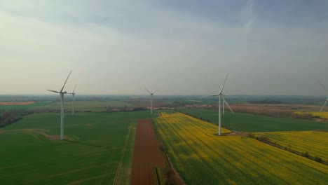 Aerogeneradores-Eólicos-Con-Palas-Girando-Sobre-Campos-De-Colores-De-La-Campiña-Inglesa