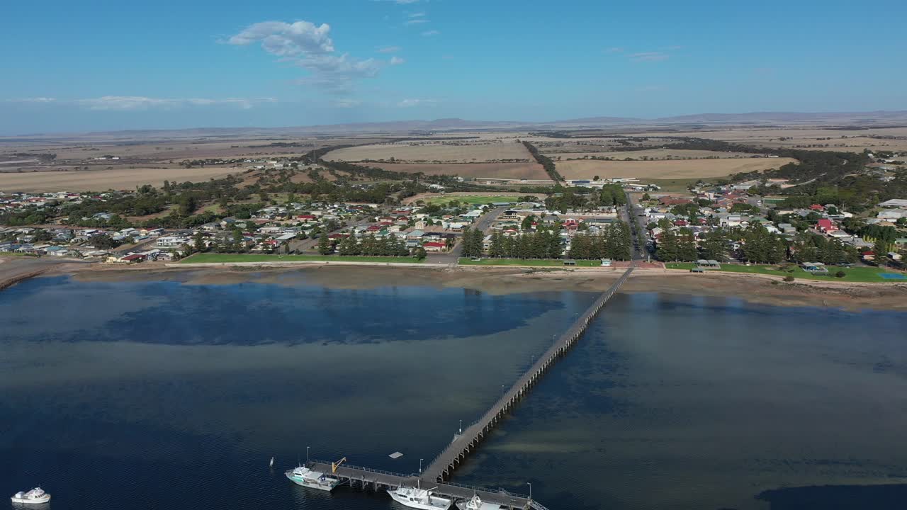 toma de drones de una pequeña ciudad costera, con un embarcadero y botes de pesca, cerca del puerto de bringon en la costa sur de australia