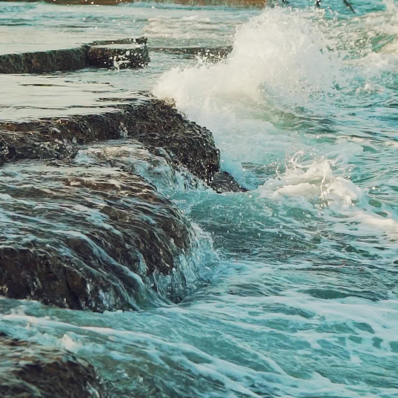 sea waves are crashing with foam on the rocks of the coast in the summer. Slow motion