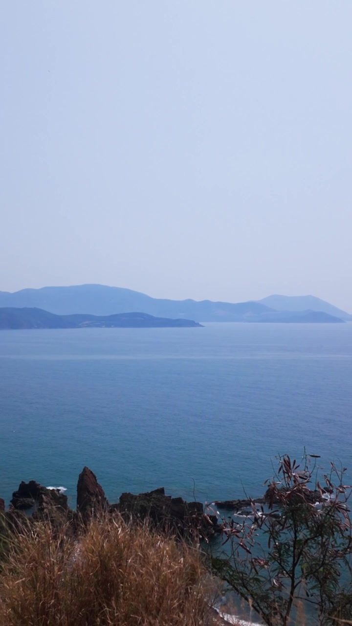 Di Diem Ngam Bien di Na Trang, Vietnam, orang-orang menikmati pemandangan laut dan air biru yang luas. Perbukitan memberikan latar belakang yang indah. Banyak yang menikmati keindahan lanskapnya
